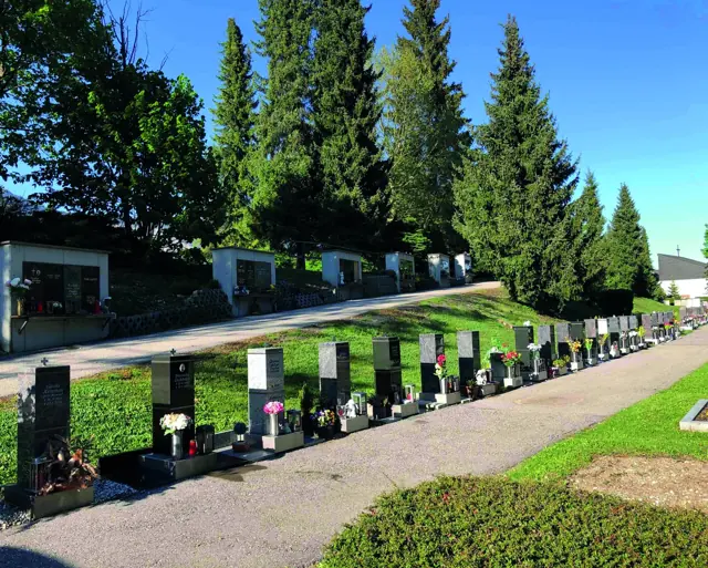 Urnensäulen entlang eines Friedhofswegs